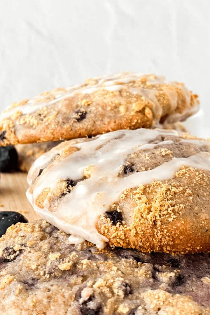Close-up of three freshly baked dessert drizzled with icing, stacked on a wooden surface.