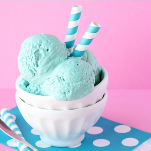 A white bowl filled with green cotton candy ice cream with swirly straws stuck into it