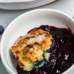 A white corning dish of southern Blueberry Cobbler.