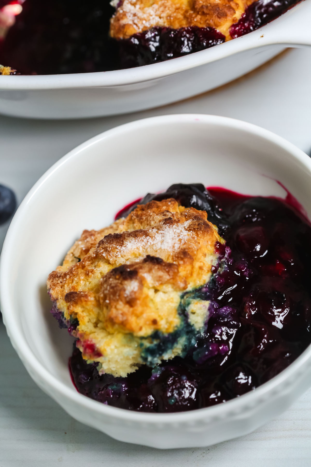 A white corning dish of southern Blueberry Cobbler.