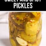 A glass jar filled with Sweet and Spicy Pickles in brine, featuring sliced pickles, garlic cloves, and red pepper flakes. Text above reads: "Crisp Sweet and Spicy Pickles.