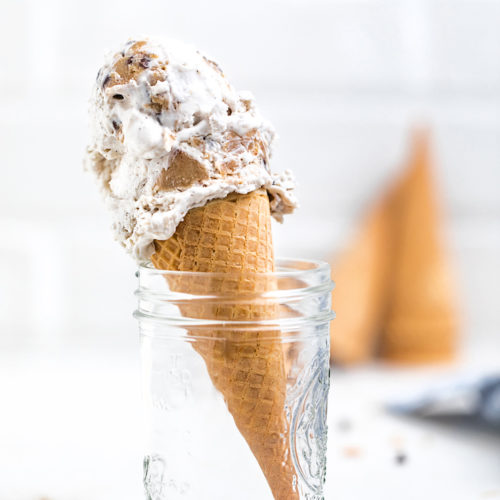 A mason jar holds a cone with a single scoop of cookie dough ice cream