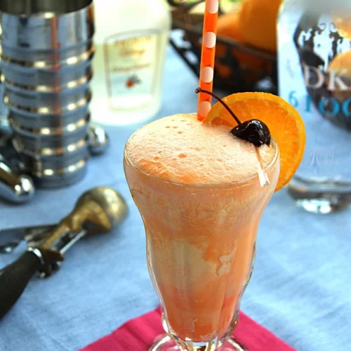 An Orange Creamsicle Cocktail garnished with an orange and a cherry