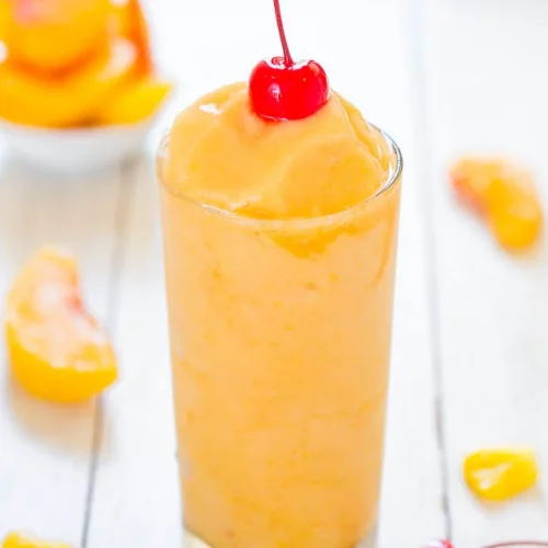 A Tropical Peach Pineapple Slushy garnished with a cherry