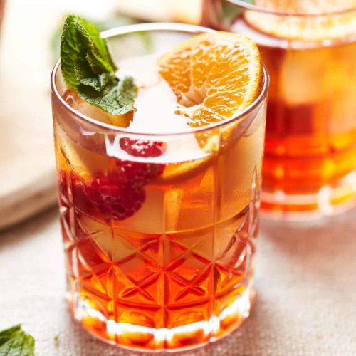 A Spiked Raspberry Sweet Tea garnished with a leaf and fruit