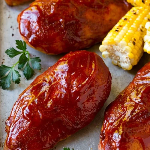 Smoked chicken breast with barbeque sauce next to corn