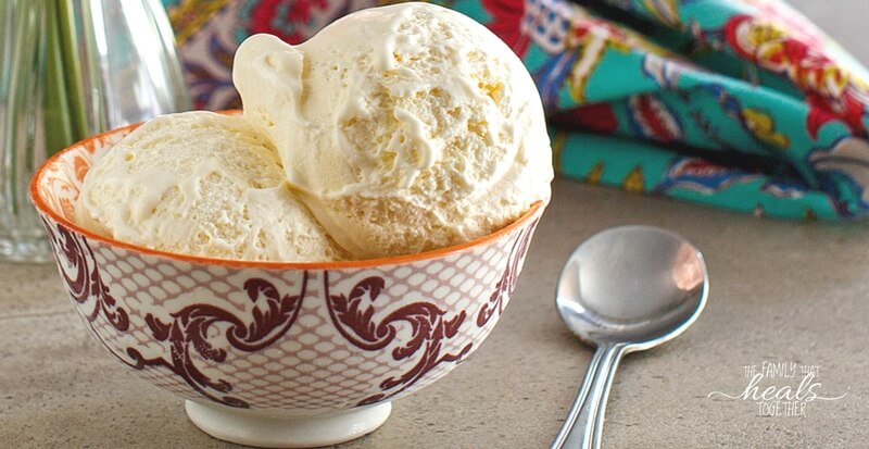 A small bowl of vanilla ice cream with a spoon next to it on the table