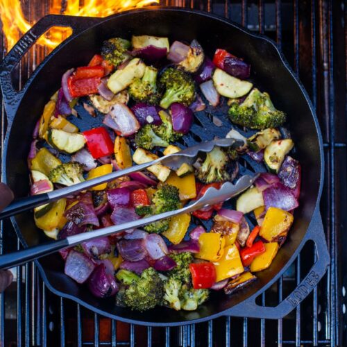 An overhead shot of a cast iron pot on a grill filled with marinated veggies