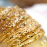 Close-up of Air Fryer Hasselback Potatoes, thinly sliced and perfectly baked, seasoned with herbs and grated cheese.