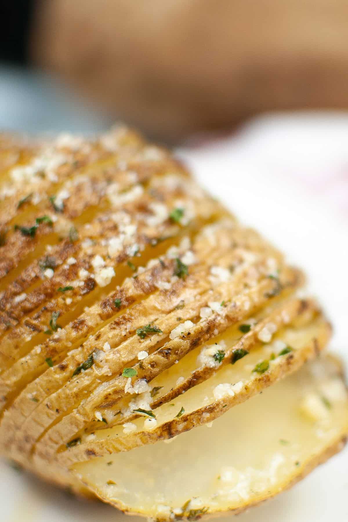 Close-up of Air Fryer Hasselback Potatoes, thinly sliced and perfectly baked, seasoned with herbs and grated cheese.