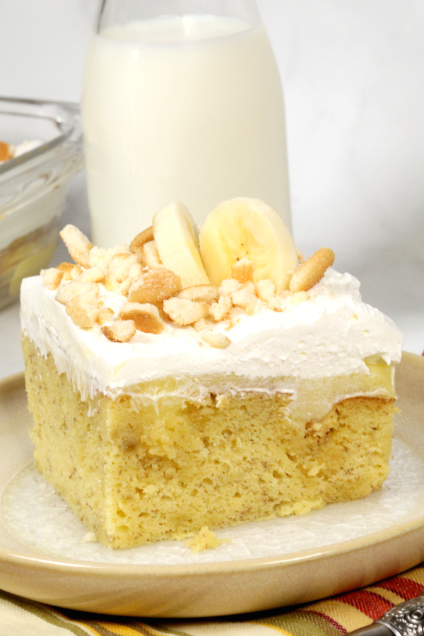 Banana Cream Poke Cake with a glass of milk.