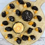 A top shot of a wooden cutting board with the oranges and chocolate on them.