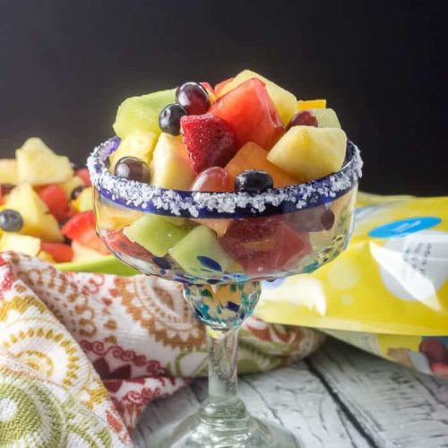 A small margarita glass is filled with fresh fruit salad, and a salted rim
