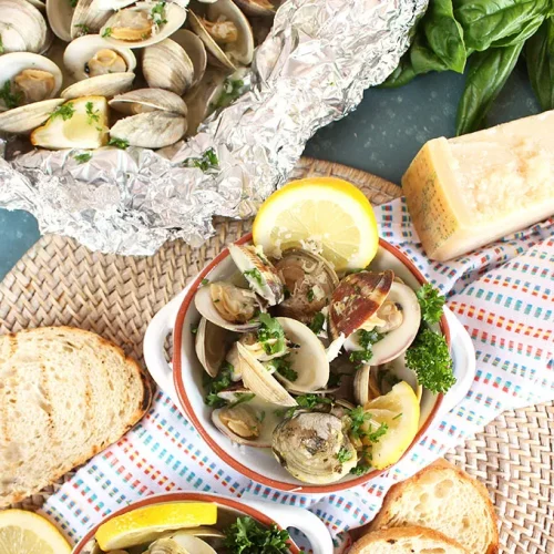 An overhead shot of several dishes with grilled clams and parsley