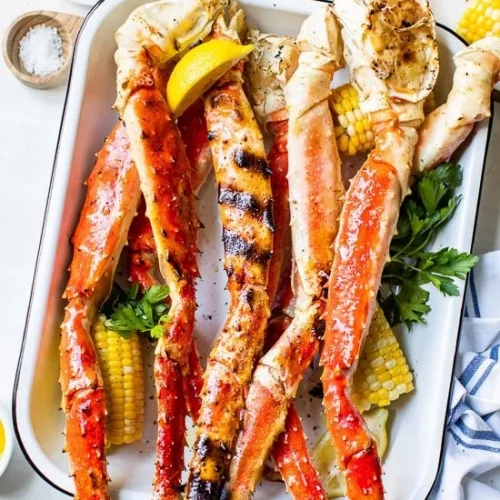 A plate of grilled crab legs with corn and lemon