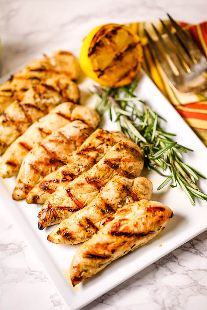 A Grilled Lemon Rosemary Chicken with rosemary on the side.