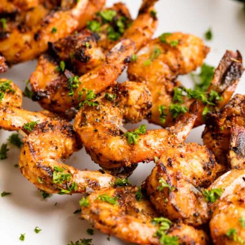 A plate of grilled shrimp on skewers garnished with parsley
