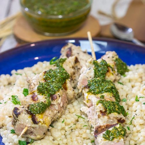 Two tun skewers sit on top of a bed of white rice, covered in a green chermoula sauce