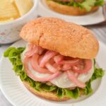 Grilled Turkey Burgers with Pickled Onions on a white plate with chips in the background.