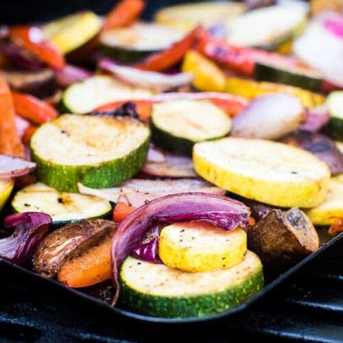 A pan filled with vegetables sits on a grill