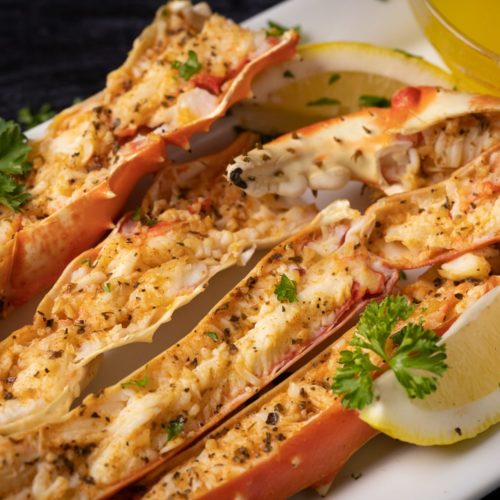 A closup of halved grilled crab legs with parsley and lemon