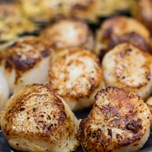 A closeup of several scallops on the grill