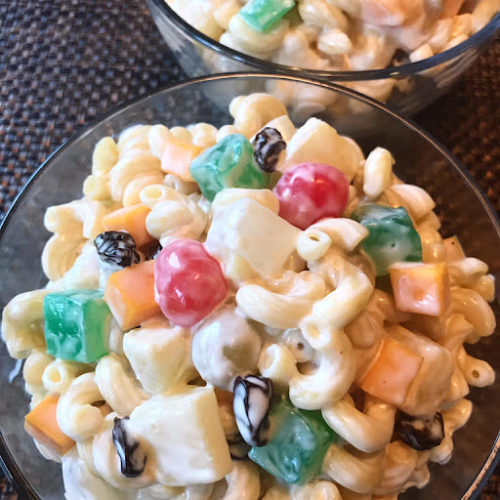 A bowl is filled with creamy macaroni and fruit