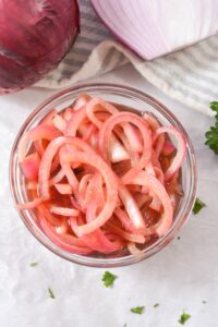 Pickled Pink Onions in a clear glass dish.