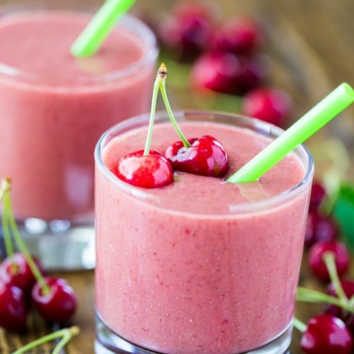 Two strawberry cherry smoothies garnished with cherries