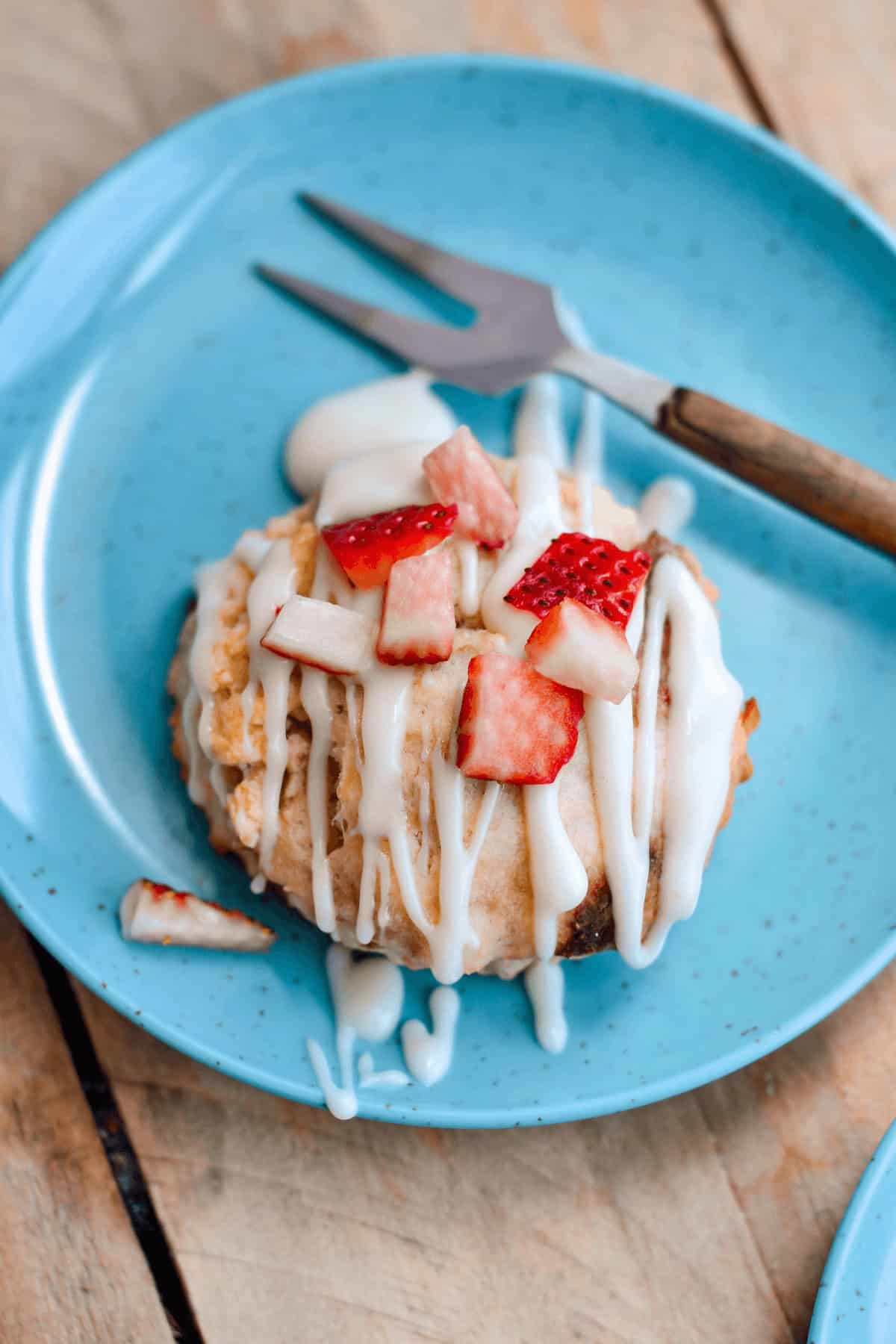 A strawberry scone on a blue plate with a fork.