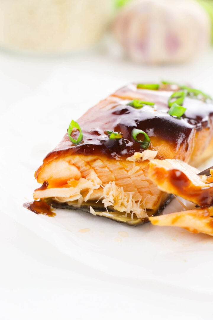 Teriyaki Glazed Salmon on a white plate with fresh herbs.