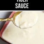 A spoonful of creamy, light-colored Tiger Sauce is held above a small square dish filled with the zesty Tiger Sauce.