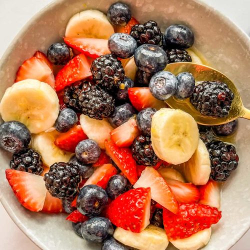 An overhead shot of a bowl filled with blackberries, strawberries, bananas, and blueberries