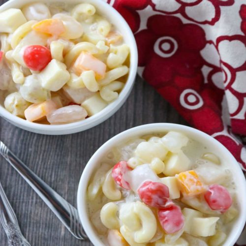 Two bowls are filled with pasta and fruit, garnished with a cherry
