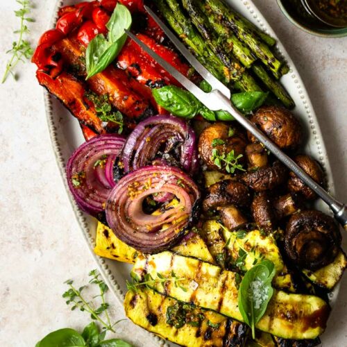 A plate of many grilled vegetables including squash, onions, mushrooms, asparagus, and peppers