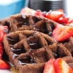 Indulge topped with syrup, sliced strawberries, and chocolate chips, served on a white plate.