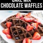 A plate of Chocolate Waffles topped with sliced strawberries, chocolate chips, and syrup sits on a table with a newspaper underneath. Text above reads "Perfect Cake Mix Chocolate Waffles.