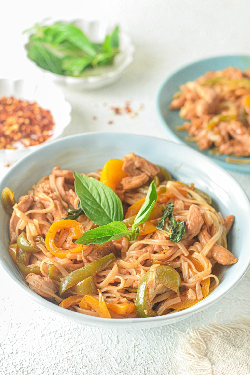 drunken chicken noodles in a white bowl with fresh herbs on top.