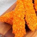 A group of Doritos Crusted Chicken strips on a wooden board.