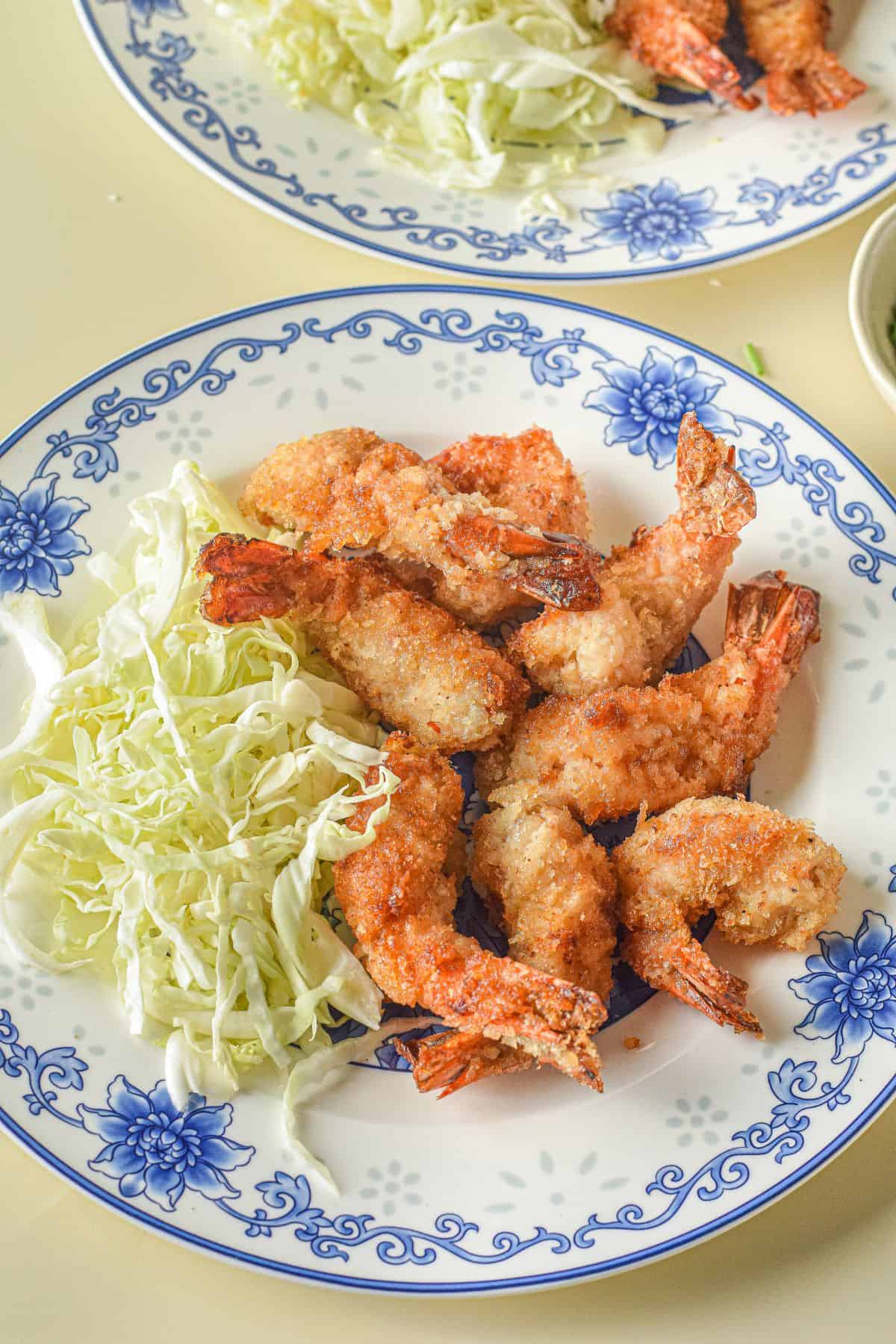 A plate of crispy Panko Shrimp and shredded cabbage, served on a white dish with blue floral patterns.