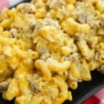 A close-up of Homemade Cheeseburger Macaroni, featuring creamy macaroni and cheese with ground beef, served on a black plate.
