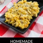 A rectangular black plate filled with creamy Homemade Cheeseburger Macaroni sits on a red and white checkered cloth, next to a pan of the same delicious dish.