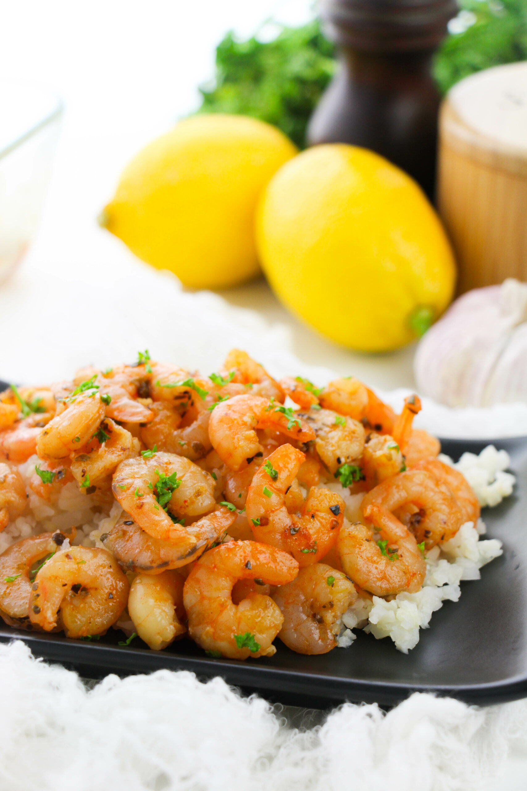 Italian Oven Baked Prawns (Shrimp) from the side with a stack of lemons.