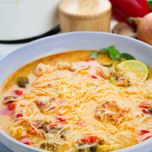 Thai Red Curry Chicken Soup is incredibly tasty and not only easy but quick to make. This recipe uses simple and whole ingredients. in a blue bowl.