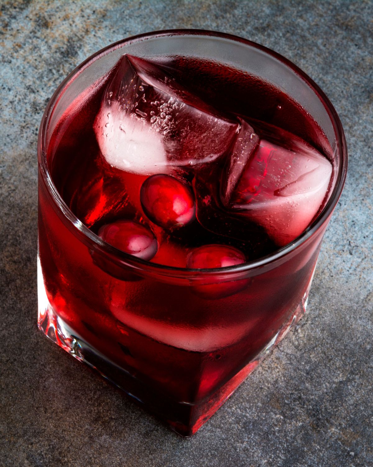 cranberry flavored moonshine in a glass with ice and cranberries