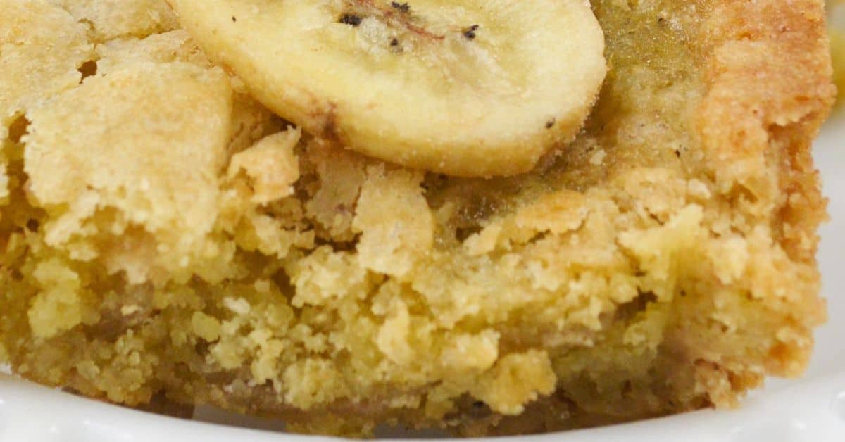 A close-up of a slice of banana bread topped with a banana slice, showing a crumbly texture—perfect inspiration for making Peanut Butter Banana Bars.
