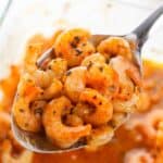 A close-up of a spoonful of seafood with more sauce visible in the background.