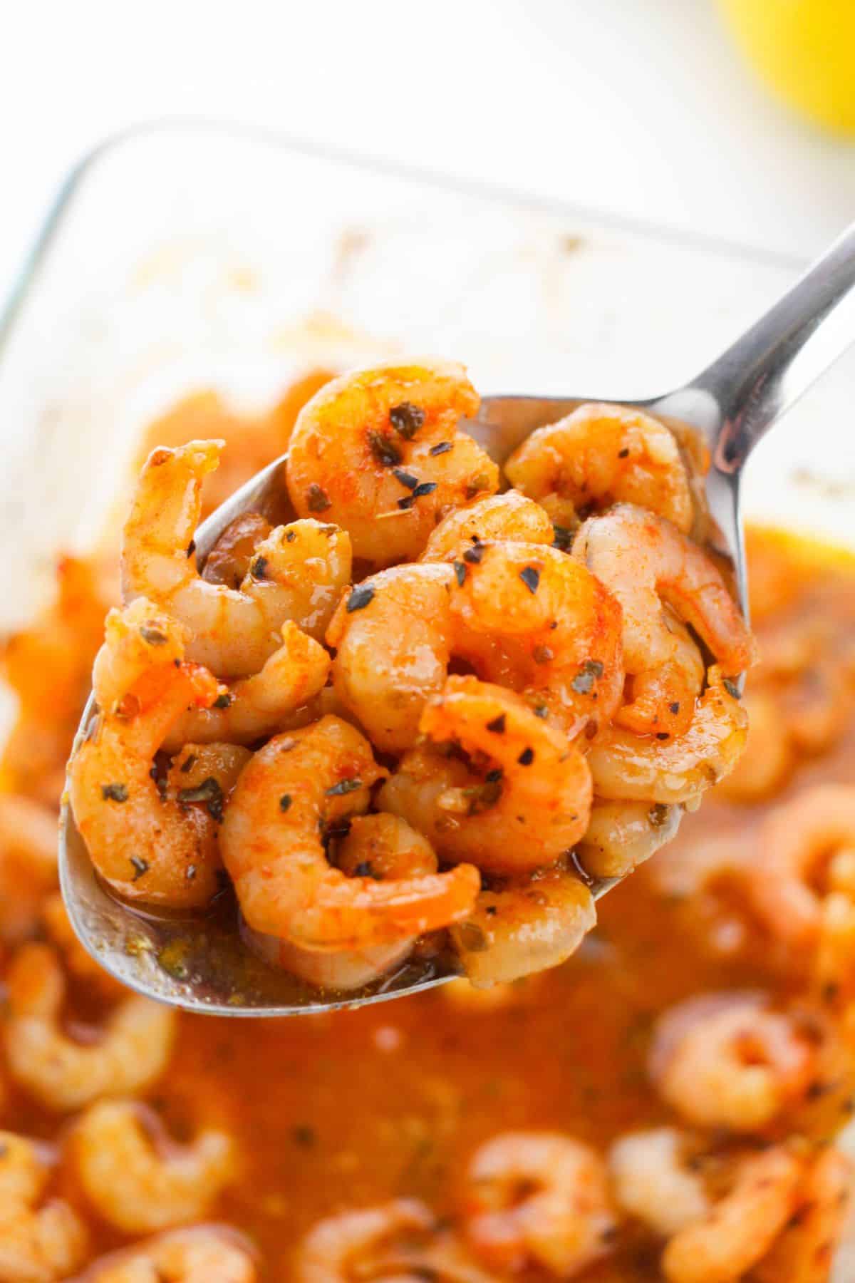 A close-up of a spoonful of seafood with more sauce visible in the background.