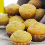 A bowl of the lemon ricotta muffins tipped on the side with the muffins slilling out.