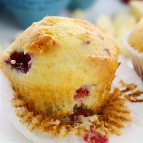 A partially eaten dessert with a crumpled white paper liner, showing a bite taken out of it.